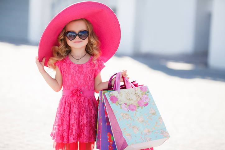 Fashionable little girl in a hat with shopping bags