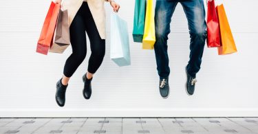 Woman and man jumping with shopping bags
