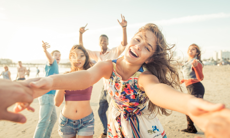 Group of friends having fun and dancing on the beach