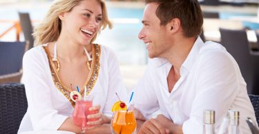 Couple eating pizza and drinking tropical drinks outside