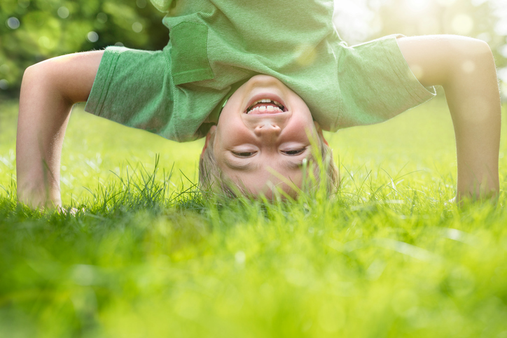 Young boy doing a headstand on the grass