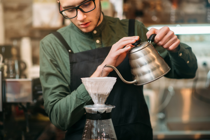 Waiter pours hot boiled water in a coffee pot