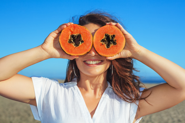 Adult woman hold in hands ripe fruit - orange papaya