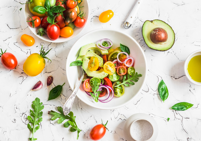 Fresh salad with tomatoes and avocado on a light background