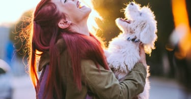 Attractive Redheaded Girl and White Puppy Smiling Together