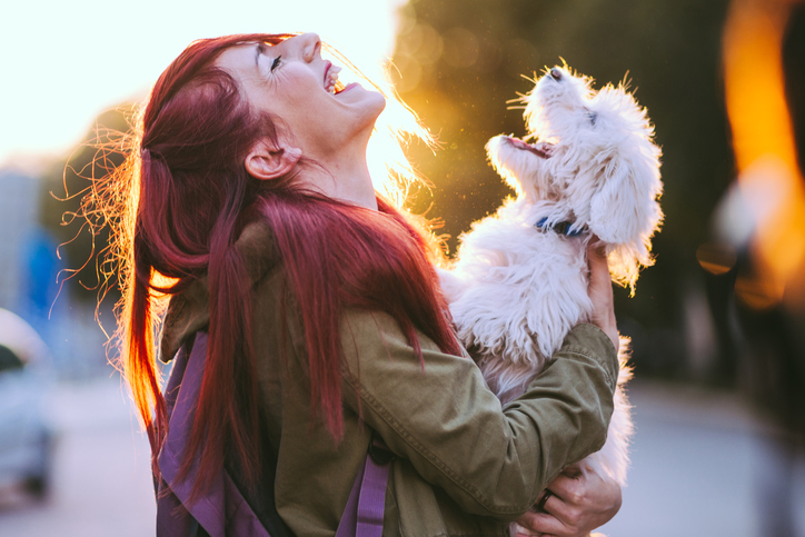 Attractive Redheaded Girl and White Puppy Smiling Together