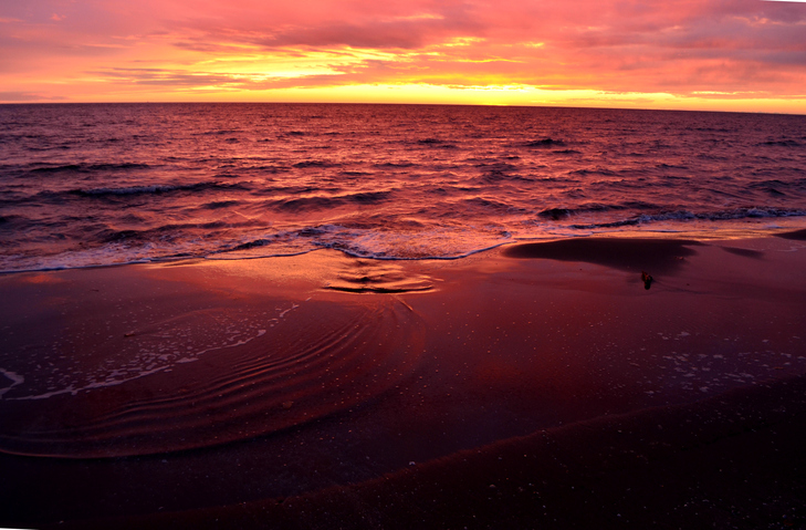 Sea waves during a colorful sunset over a romantic beach